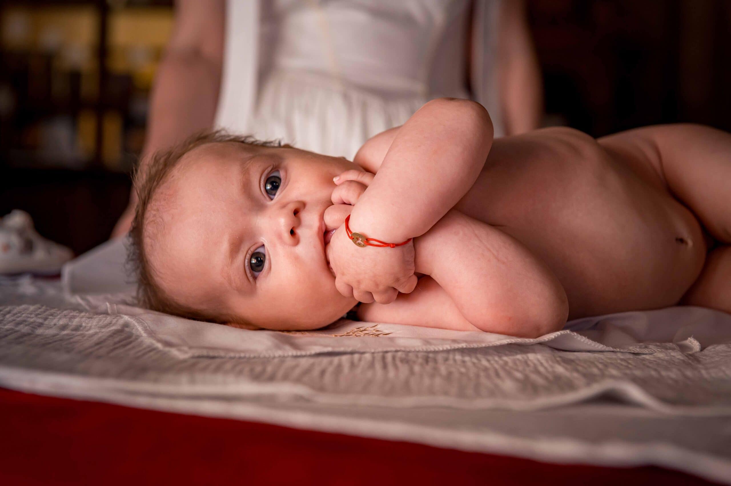 Adorable baby with bright eyes lying on a changing table, capturing a moment from a children's photo.